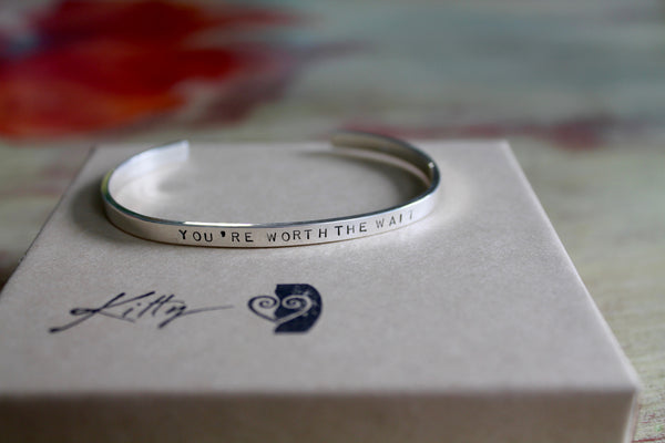 Message is You're Worth the Wait stamped on top of silver bracelet