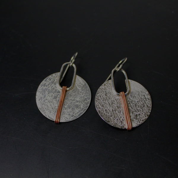 Silver circle with copper lines earrings shown on black background