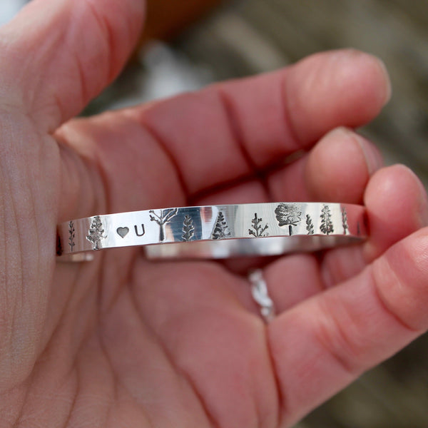 Personalized Trees bracelet with a heart and a U in between the trees on top of the bracelet.