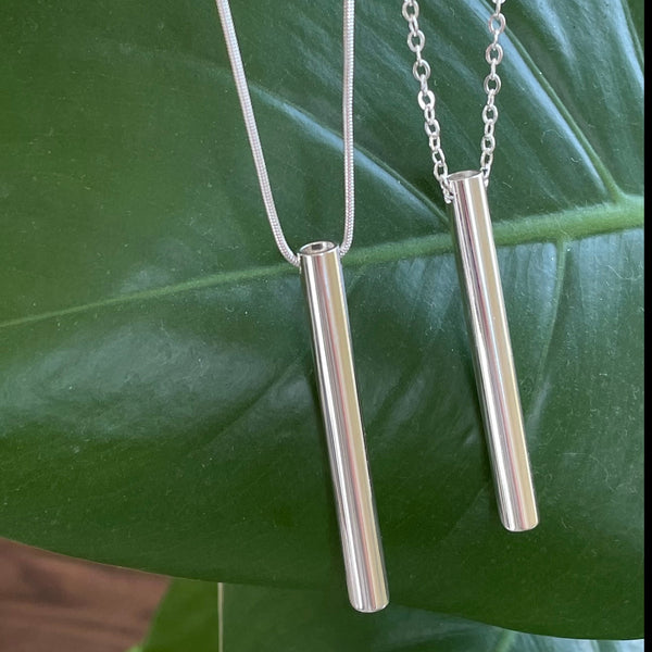 Breathing tool necklaces shown in front of a green leaf 