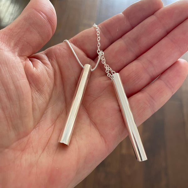 Breathing tool necklaces shown on hand with two different chain styles