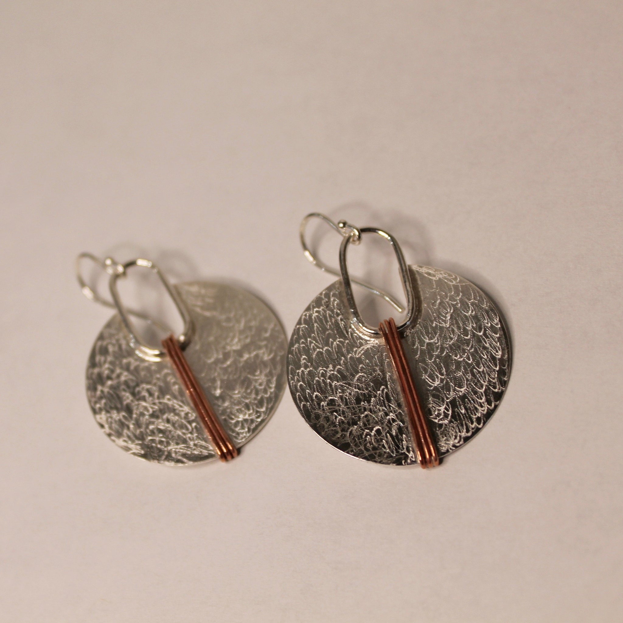 silver circle with copper lines earrings on white background