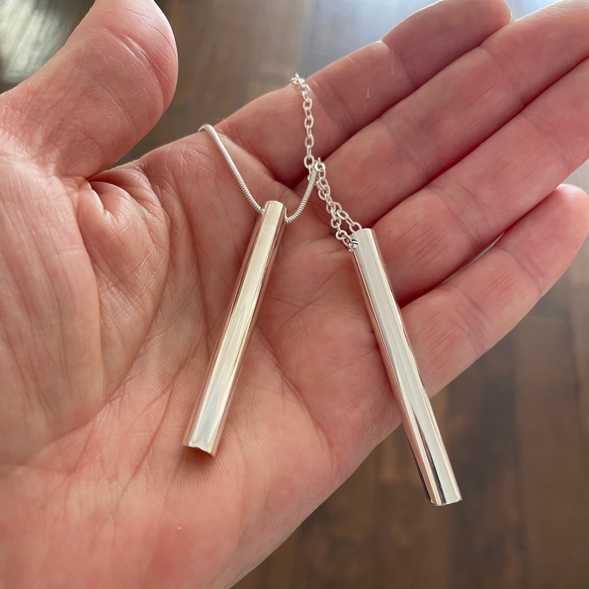 Breathing tool necklaces shown on hand with two different chain styles