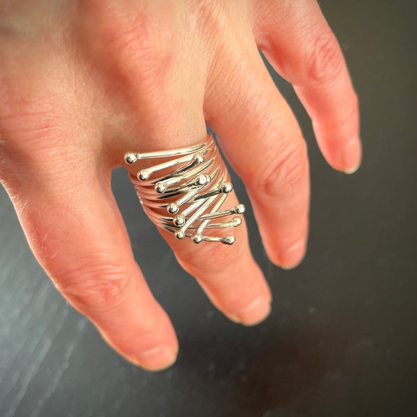 Silver Embrace ring shown with hand pointing downward angle