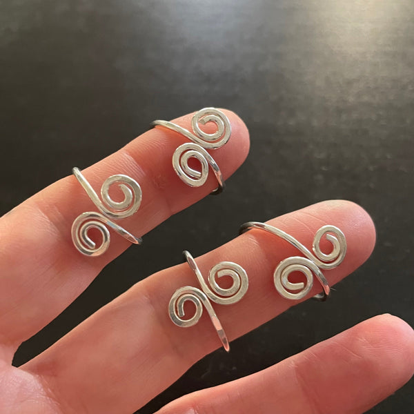 four double swirl rings shown on fingers